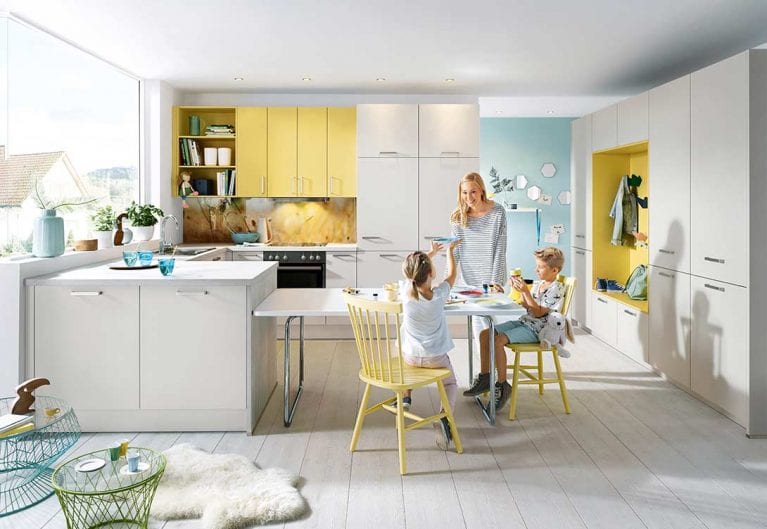Foto eines hellen Küchen- und Essbereichs mit einer Frau mit zwei Kindern, die am Esstisch sitzen