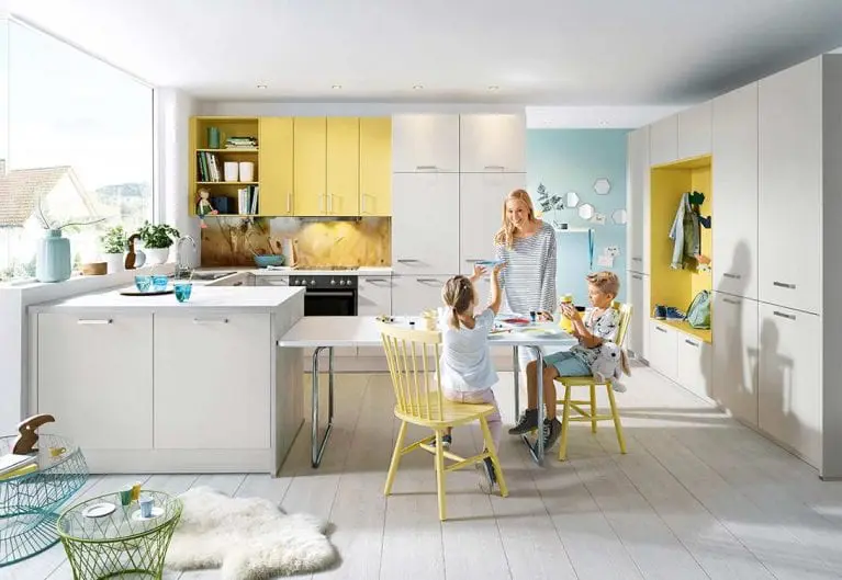 Foto eines hellen Küchen- und Essbereichs mit einer Frau mit zwei Kindern, die am Esstisch sitzen