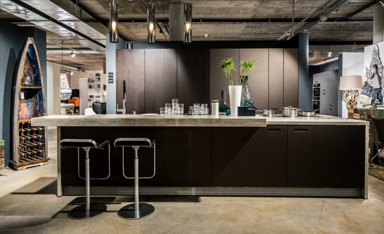 Foto einer luxuriösen Küche in Beton-Optik und Holz mit integrierter Bar und Barhockern