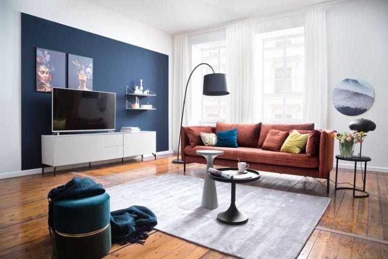 Wohnzimmer mit petrolfarbener Wand und organgenem Sofa