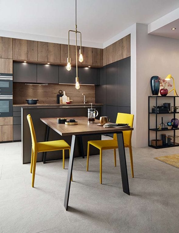 Moderne Küche aus Titanfronten mit Kochinsel und Esstisch mit gelben Stühlen vor der Insel
