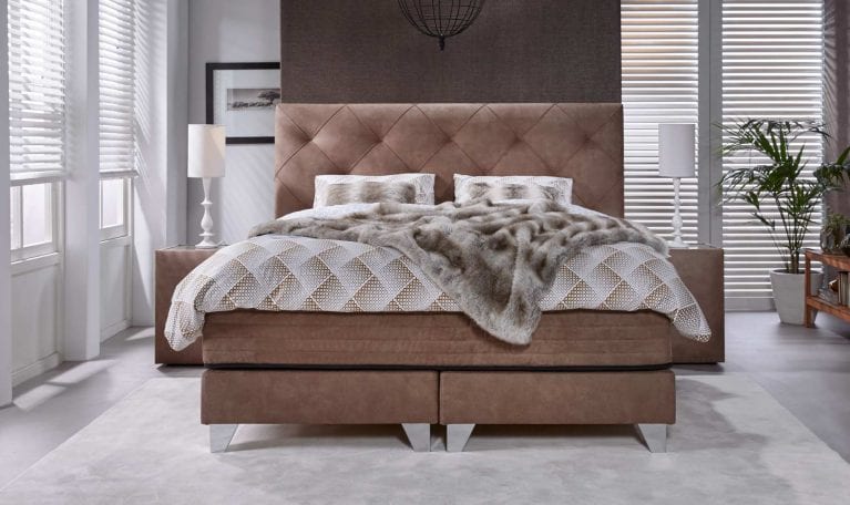 Braunes Serta Bett Magnifique mit romantischer Steppung am Kopfteil.