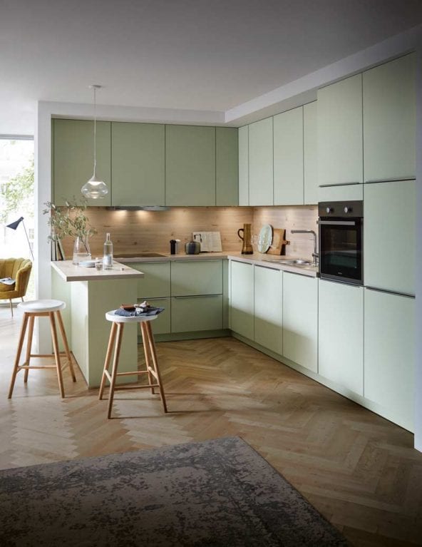 Contur Küche mit Küchentheke in Pastellgrünen-Satin-Fronten und Holzoptik als Nischenverkleidung