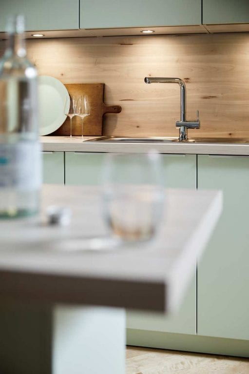 Contur Küche mit Pastellgrünen-Satin-Fronten und Holzoptik als Nischenverkleidung