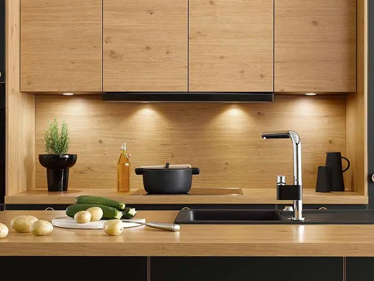 Küchenfront aus Holz in schöner Asteiche mit integrierter Küchenbeleuchtung und schwarzen Kontrastfronten