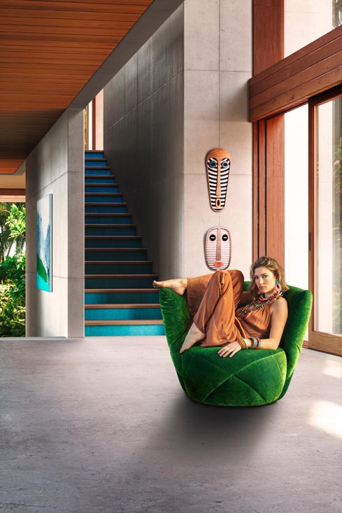 Bretz Sessel in Samtgrün mit Frau in orangenen Jumpsuit darauf