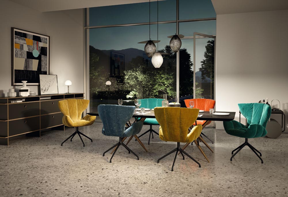Bretz Stühle in allen möglichen Farben stehen um den Esstisch herum