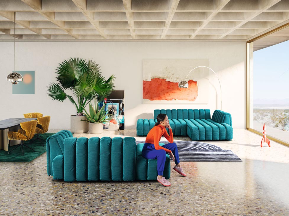 Petrolfarbenes Bretz Sofa Mooncraft steht in einer Penthouse Wohnung mit einer dunkelhaarigen Frau