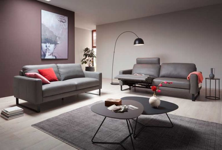 Graues Ledersofa mit verstellbarer Fuss- und Rückenlehne steht in einem modernen Wohnzimmer.