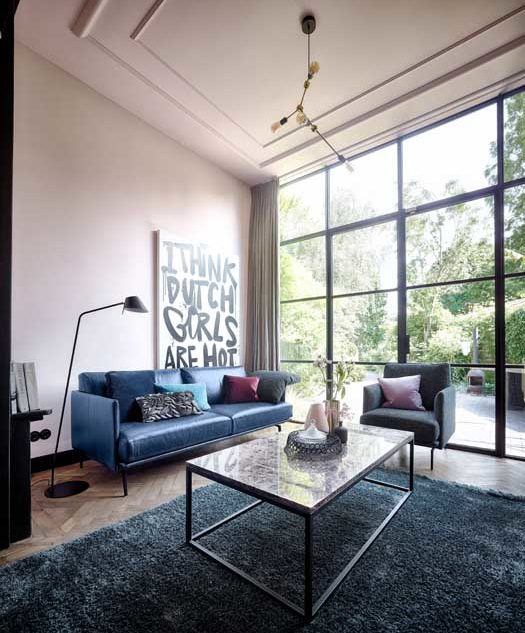 Blaues 3-Sitzer Ledersofa in einem grossen Wohnzimmer mit hohen Decken und industriellem Flair